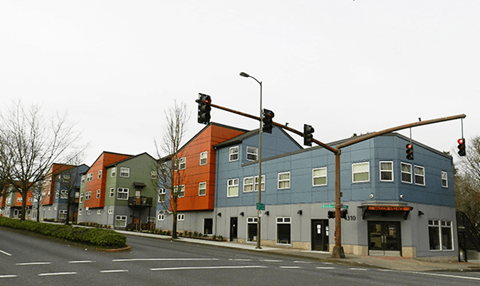 a row of buildings on a street corner at a traffic light
